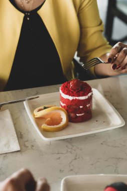 Bir kafede pasta yiyen bir kadının yakın çekimi.