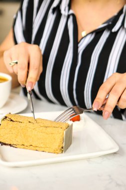 Bir kafede pasta yiyen bir kadının yakın çekimi.