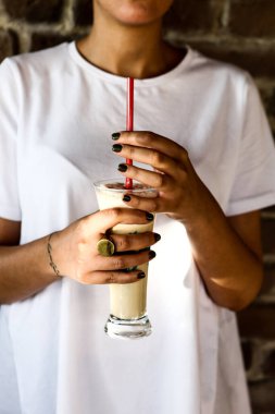 Sütlü buzlu kahve. Buzlu kahve. Elinde bir bardak buzlu kahve tutan kadın..