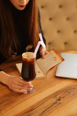 Sütlü buzlu kahve. Buzlu kahve. Elinde bir bardak buzlu kahve tutan kadın..