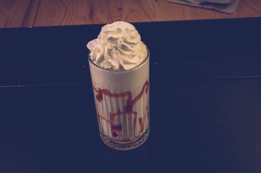 Bir bardak ahududu milkshake, krem şanti ve taze ahududu.