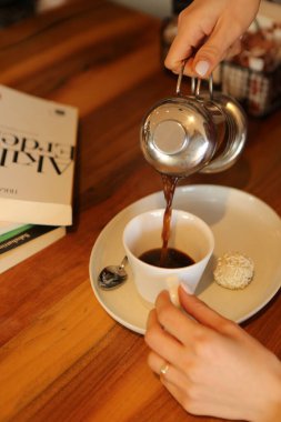 Kitap ya da dergi okurken bir fincan kahve.