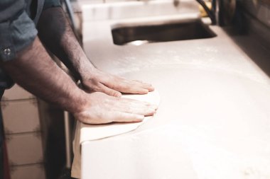 Pizza şefi ticari bir mutfakta sosu tabana koydu.