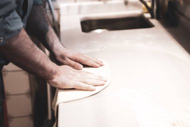 Pizza şefi ticari bir mutfakta sosu tabana koydu.