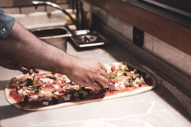 Pizza şefi ticari bir mutfakta sosu tabana koydu.