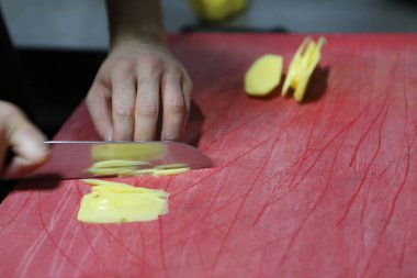 İnsan yemek pişirmek için patatesleri doğrar..