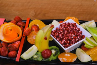 Lezzetli karışık meyveler ve dilimlenmiş meyvelerle dolu bir tabak.