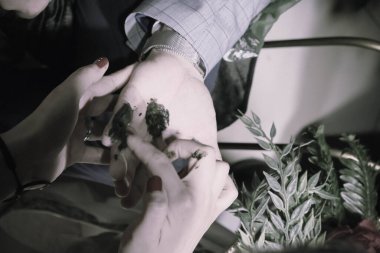 Gelinin kına gecesinde elini koyuyor. 