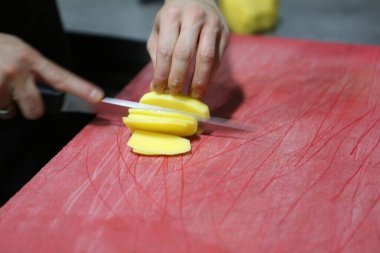 İnsan yemek pişirmek için patatesleri doğrar..