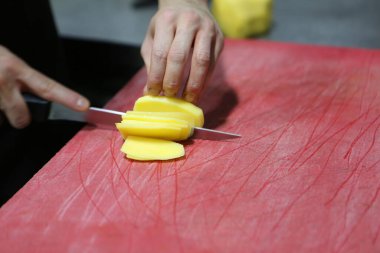 İnsan yemek pişirmek için patatesleri doğrar..