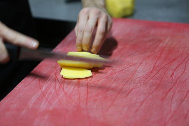 İnsan yemek pişirmek için patatesleri doğrar..