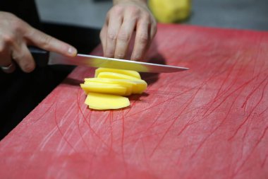 İnsan yemek pişirmek için patatesleri doğrar..