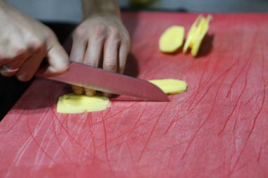 İnsan yemek pişirmek için patatesleri doğrar..
