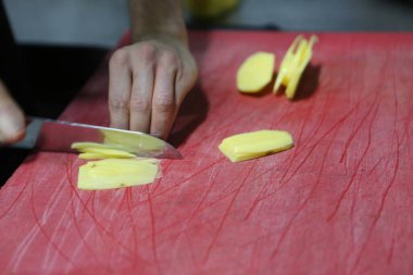 İnsan yemek pişirmek için patatesleri doğrar..