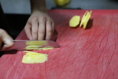 İnsan yemek pişirmek için patatesleri doğrar..