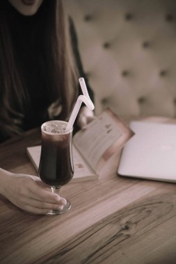 Kitap ya da dergi okurken bir fincan kahve.