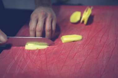İnsan yemek pişirmek için patatesleri doğrar..