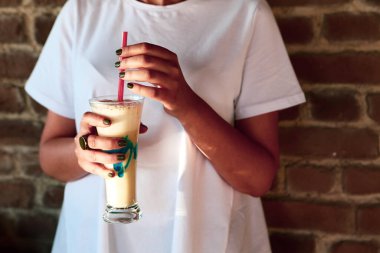 Sütlü buzlu kahve. Buzlu kahve. Elinde bir bardak buzlu kahve tutan kadın..