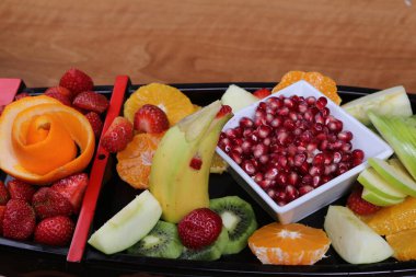Lezzetli karışık meyveler ve dilimlenmiş meyvelerle dolu bir tabak.