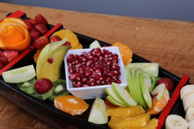 Lezzetli karışık meyveler ve dilimlenmiş meyvelerle dolu bir tabak.