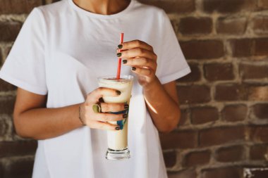 Sütlü buzlu kahve. Buzlu kahve. Elinde bir bardak buzlu kahve tutan kadın..