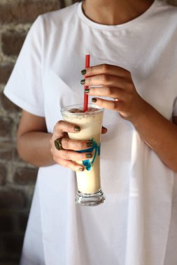 Sütlü buzlu kahve. Buzlu kahve. Elinde bir bardak buzlu kahve tutan kadın..