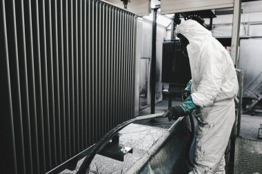 Fabrika, çalışanlar iş yerinde kimyasal koruyucu giysi giyerler. Boya püskürtme.