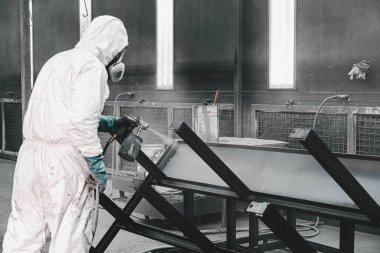 Fabrika, çalışanlar iş yerinde kimyasal koruyucu giysi giyerler. Boya püskürtme.
