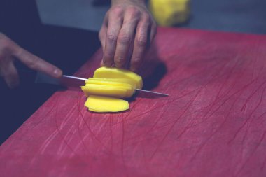 İnsan yemek pişirmek için patatesleri doğrar..