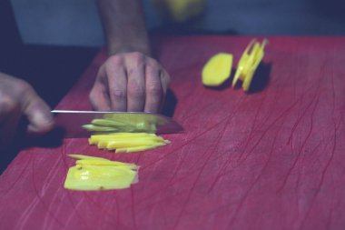 İnsan yemek pişirmek için patatesleri doğrar..