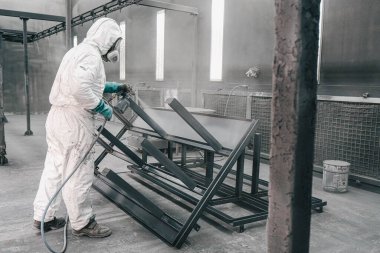 Fabrika, çalışanlar iş yerinde kimyasal koruyucu giysi giyerler. Boya püskürtme.