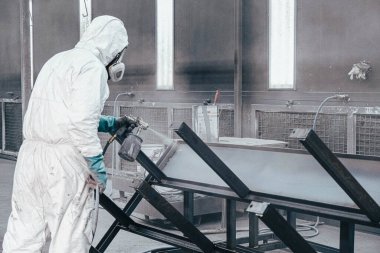Fabrika, çalışanlar iş yerinde kimyasal koruyucu giysi giyerler. Boya püskürtme.