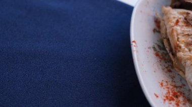 Kızarmış deniz çerezi (cupra) beyaz tabakta soğan, bahçe roketi ve limon dilimli balık.