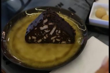 Genç bir kadın mozaik bir pasta dilimleyip yiyor..