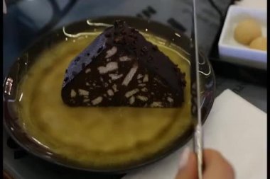 Genç bir kadın mozaik bir pasta dilimleyip yiyor..