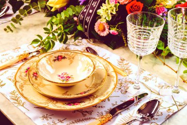 Güzel bir tabak ve mükemmel renkte çiçekler lüks bir masada duruyor.