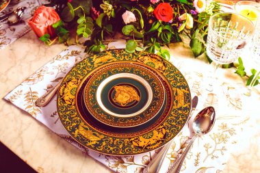 Güzel bir tabak ve mükemmel renkte çiçekler lüks bir masada duruyor.