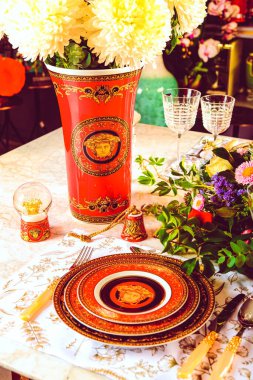 Güzel bir tabak ve mükemmel renkte çiçekler lüks bir masada duruyor.