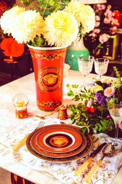 Güzel bir tabak ve mükemmel renkte çiçekler lüks bir masada duruyor.