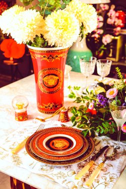 Güzel bir tabak ve mükemmel renkte çiçekler lüks bir masada duruyor.