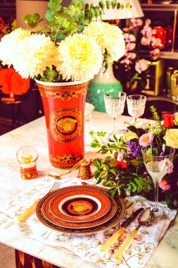 Güzel bir tabak ve mükemmel renkte çiçekler lüks bir masada duruyor.