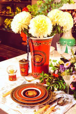 Güzel bir tabak ve mükemmel renkte çiçekler lüks bir masada duruyor.