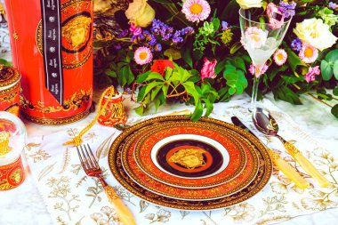 Güzel bir tabak ve mükemmel renkte çiçekler lüks bir masada duruyor.