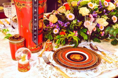 Güzel bir tabak ve mükemmel renkte çiçekler lüks bir masada duruyor.