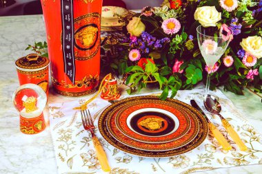 Güzel bir tabak ve mükemmel renkte çiçekler lüks bir masada duruyor.