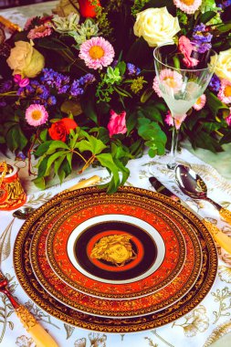 Güzel bir tabak ve mükemmel renkte çiçekler lüks bir masada duruyor.