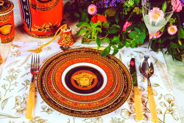 Güzel bir tabak ve mükemmel renkte çiçekler lüks bir masada duruyor.