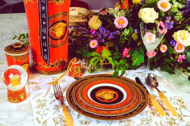 Güzel bir tabak ve mükemmel renkte çiçekler lüks bir masada duruyor.