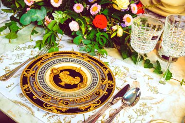 Güzel bir tabak ve mükemmel renkte çiçekler lüks bir masada duruyor.