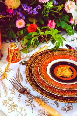 Güzel bir tabak ve mükemmel renkte çiçekler lüks bir masada duruyor.